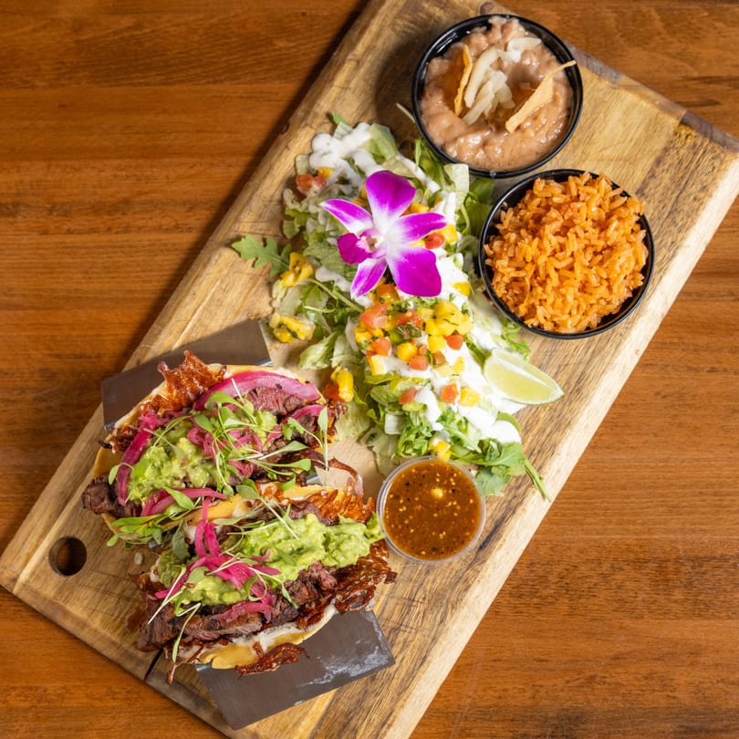 California Tacos Cantina and Distillery's steak tacos with guacamole, pickled onions, and microgreens, served with rice, beans, and salad.